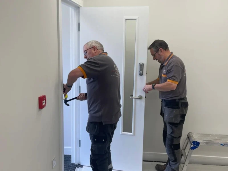 Two Crow team members dismantling a door frame.